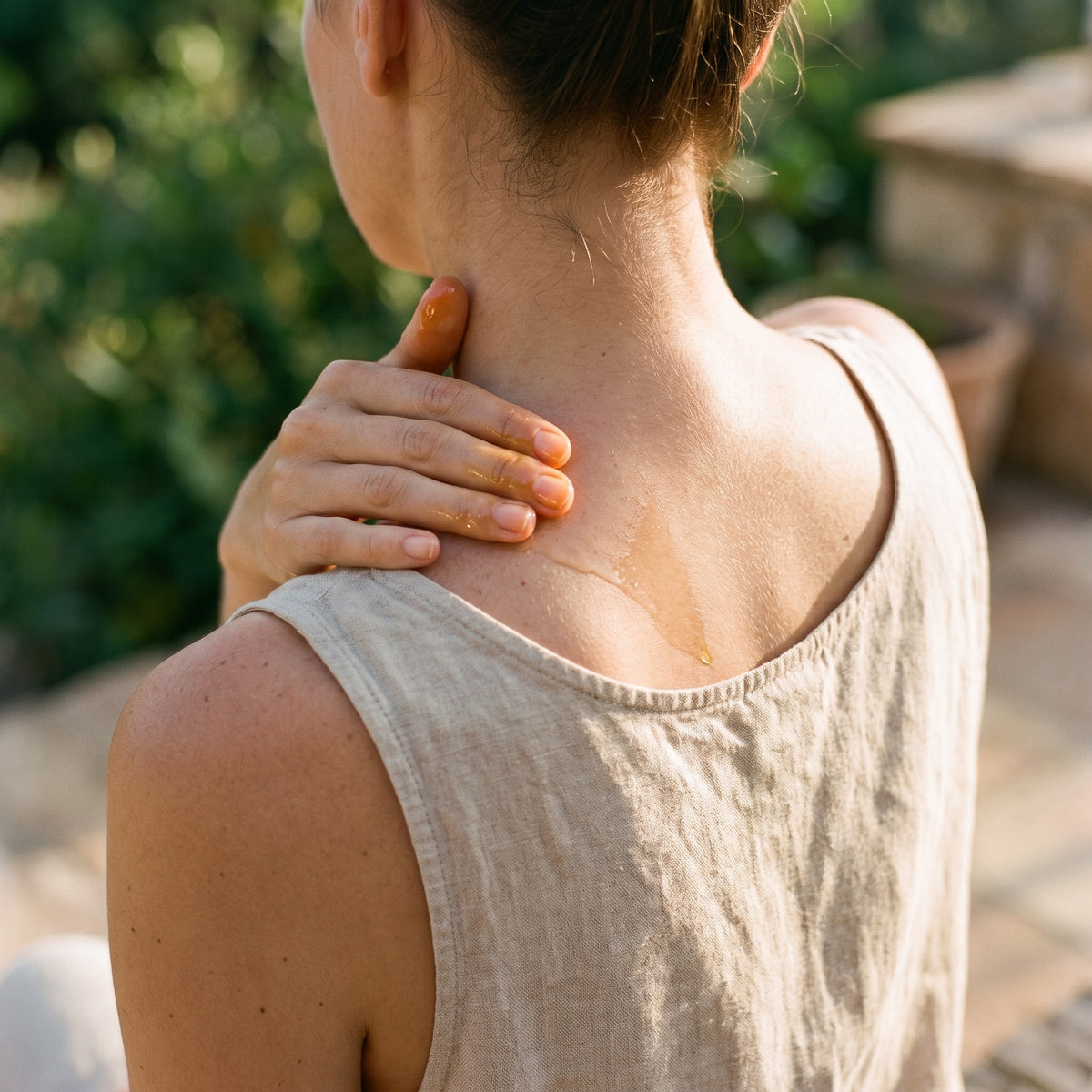 Massaging a little oil into the shoulder and neck outdoors in summer light