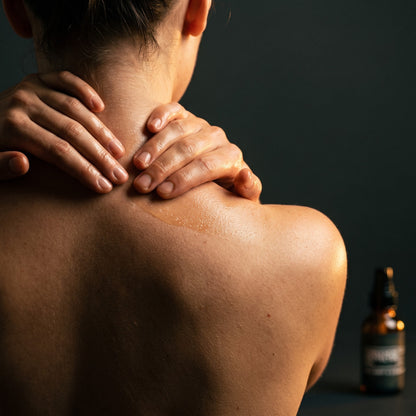Hands working oil into the neck and shoulders in warm evening light